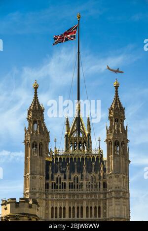 LONDRA, INGHILTERRA - GIUGNO 2018: La Victoria Tower nel Palazzo di Westminster con la bandiera Union Jack in volo e un jet di passaggio Foto Stock