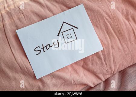 Parole su carta, rimanere a casa. Una lettera su un cuscino che chiede di rimanere a casa. Primo piano, il concetto di ricreazione e salute.quarantena e isolamento di Foto Stock