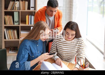 Studenti che fanno fogli di trucco per l'esame in biblioteca Foto Stock