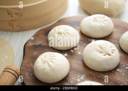 Tavole di legno con gnocchi di baozi crudi su tavola Foto Stock