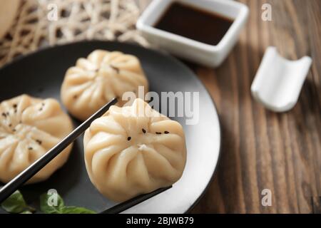 Tenere baozi gnocchi con bacchette sopra il tavolo, primo piano Foto Stock