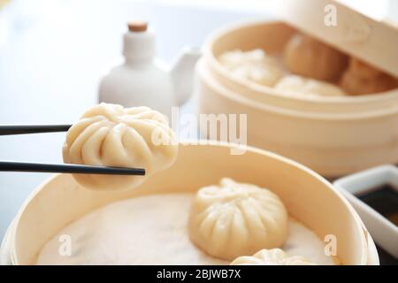 Tenere baozi gnocchi con bacchette su bambù vaporiera, primo piano Foto Stock