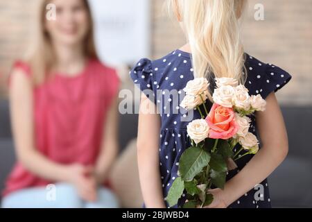 Carino ragazza tenendo fiori per la madre dietro la schiena, closeup Foto Stock