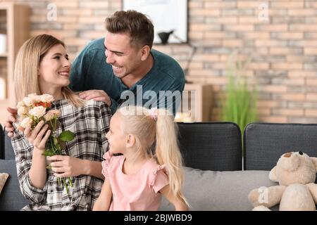 Donna felice che riceve i fiori da marito e figlia a casa Foto Stock