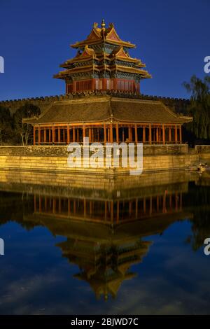 La torre nord-occidentale del Museo del Palazzo della Città Proibita a Pechino, Cina, si riflette nel fossato dell'acqua di notte Foto Stock