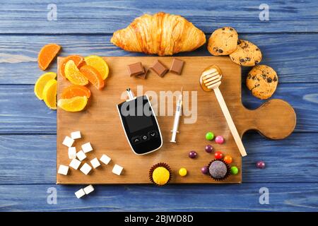 Glucometro digitale, siringa e dolci sul tavolo. Dieta per il diabete Foto Stock