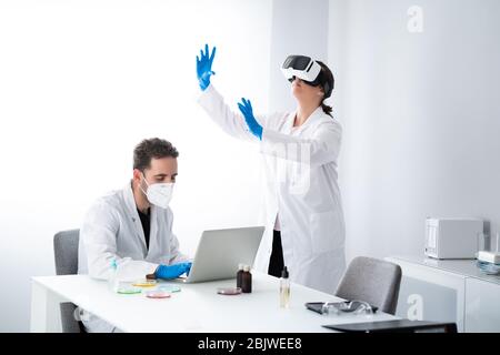 Giovani scienziati o ricercatori che lavorano nel moderno laboratorio di scienze biologiche. L'uomo lavora con i campioni in un piatto di Petri e la donna è indossata Foto Stock