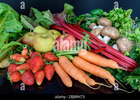 Composizione fresca e sana di frutta e verdura di stagione biologica e cruda, isolata su sfondo scuro. Foto Stock