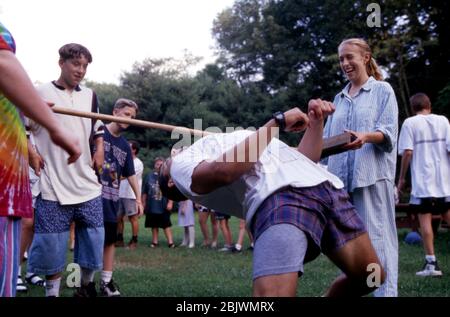 Il ragazzo teenage danza limbo durante il campo estivo nella campagna Michigan, USA Foto Stock