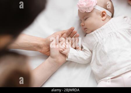 I genitori tengono la mano del bambino sul letto Foto Stock