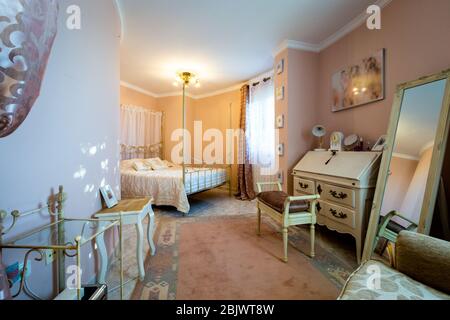 Ampia e accogliente camera da letto in stile classico, mobili beige, tappeti e specchi. Foto Stock