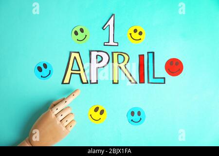 Frase '1 aprile' e manichino mano su sfondo a colori. Composizione del giorno dello sciocco Foto Stock
