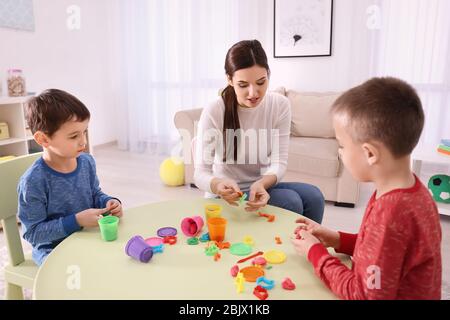 Nanny e ragazzi che scolpiscono dalla plastilina a casa Foto Stock