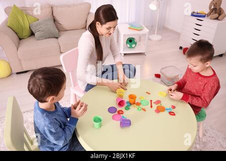 Nanny e ragazzi che scolpiscono dalla plastilina a casa Foto Stock