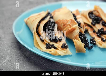 Pancake sottili con delizioso caviale nero sul piatto Foto Stock