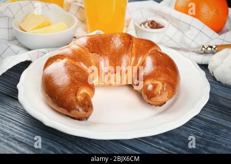 Piatto con fresco e gustoso rotolo di mezzaluna su tavolo di legno Foto Stock