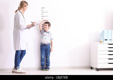 Medico donna Misurazione altezza del ragazzino in clinica Foto Stock