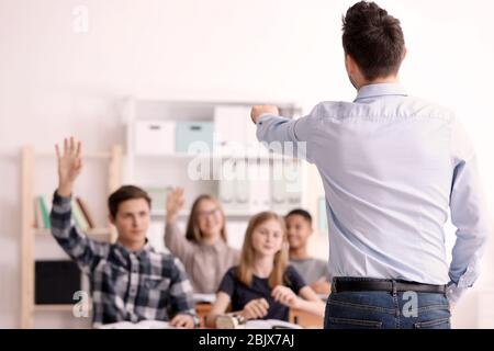 Gruppo di adolescenti che fanno i compiti con l'insegnante in classe Foto Stock