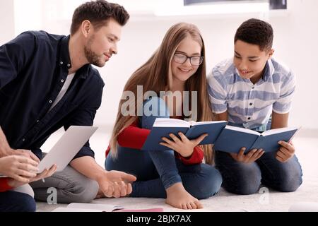 Gruppo di adolescenti che fanno i compiti con l'insegnante al chiuso Foto Stock