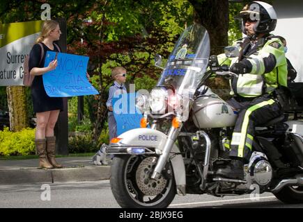 (200430) -- SURREY (CANADA), 30 aprile 2020 (Xinhua) -- persone che hanno i segni guardare un motociclo alla Royal Canadian Mounted Police (RCMP) sede centrale in Surrey, Canada, 30 aprile 2020. Giovedì, nel Surrey del Canada, si è tenuta una motocicletta commemorativa di soccorritori per onorare le vittime del massacimo sparo in Nuova Scozia. (Foto di Liang Sen/Xinhua) Credit: Xinhua/Alamy Live News Foto Stock