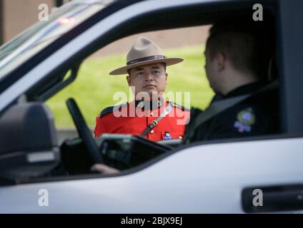 (200430) -- SURREY (CANADA), 30 aprile 2020 (Xinhua) -- UN veicolo di polizia passa da un ufficiale della polizia montata canadese reale (RCMP) durante un motociclo in Surrey, Canada, 30 aprile 2020. Giovedì, nel Surrey del Canada, si è tenuta una motocicletta commemorativa di soccorritori per onorare le vittime del massacimo sparo in Nuova Scozia. (Foto di Liang Sen/Xinhua) Credit: Xinhua/Alamy Live News Foto Stock