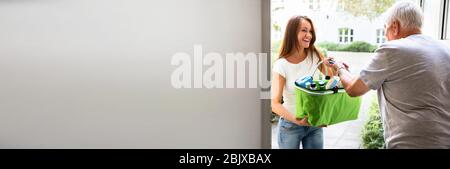 Giovane Caregiver che aiuta Senior a trasportare generi alimentari a porta Foto Stock