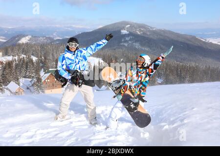 Coppia con snowboard divertirsi sulla pista da sci presso la località innevata. Vacanze invernali Foto Stock