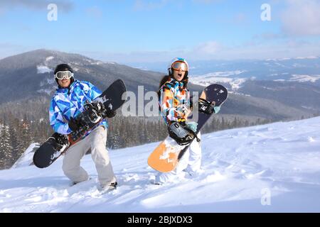 Coppia con snowboard divertirsi sulla pista da sci presso la località innevata. Vacanze invernali Foto Stock