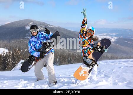 Coppia con snowboard divertirsi sulla pista da sci presso la località innevata. Vacanze invernali Foto Stock