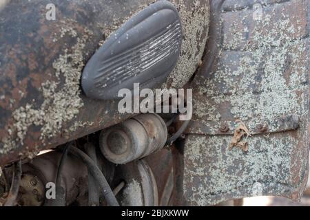 Parte del motore e del serbatoio di una vecchia moto retrò ricoperta di ruggine, sporco e muschio. Foto Stock