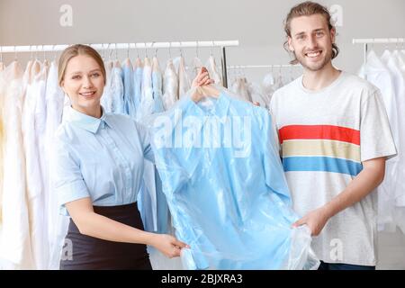Lavoratore dando vestiti a client in moderno a secco del filtro Foto Stock