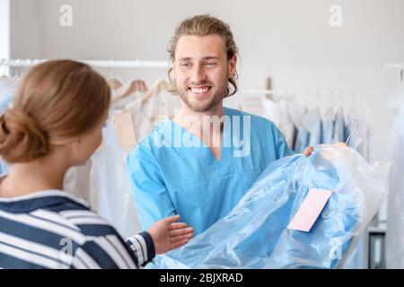 Lavoratore di sesso maschile che danno i vestiti a client in moderno a secco del filtro Foto Stock