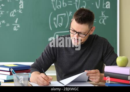 Bello insegnante maschio controllo compiti in classe Foto Stock