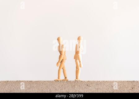 Due figure umane in legno che si ergono su un blocco di cemento con le loro spalle l'una all'altra Foto Stock