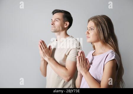 I religiosi giovane in preghiera a Dio su sfondo grigio Foto Stock