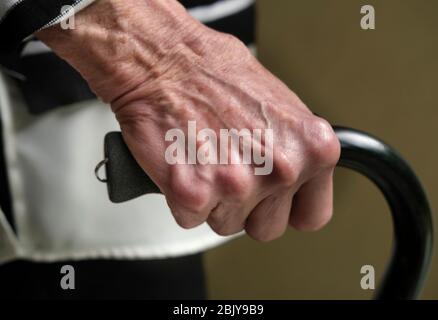 Primo piano di mano di donna anziana che tiene canna Foto Stock