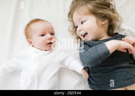 Fratelli (2-5 mesi, 2-3) sdraiati sul letto Foto Stock