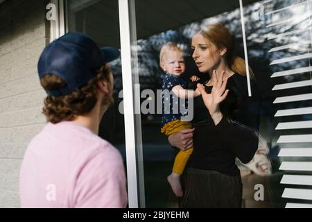 Madre con figlia (2-3) che parla con l'uomo attraverso la finestra Foto Stock