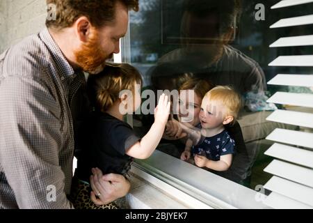 Famiglia con figlie (2-3) che visita attraverso la finestra Foto Stock