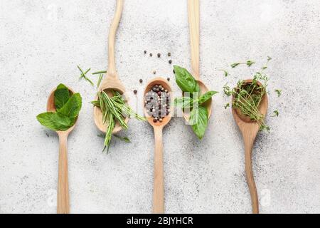 Cucchiai con diverse erbe aromatiche e spezie su sfondo chiaro Foto Stock