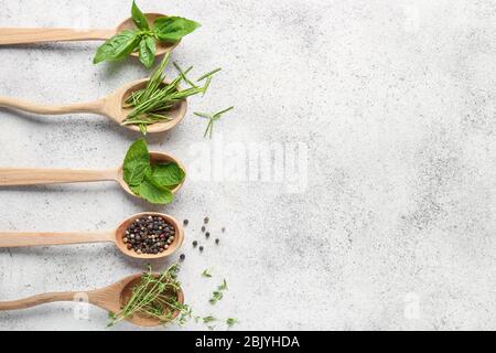 Cucchiai con diverse erbe aromatiche e spezie su sfondo chiaro Foto Stock