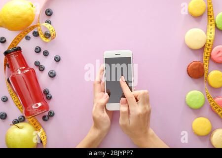 Mani femminili con telefono cellulare, prodotti e nastro di misurazione sul colore di sfondo. La perdita di peso concept Foto Stock