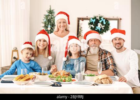 La famiglia felice in Santa Claus cappelli festeggia il Natale a casa Foto Stock