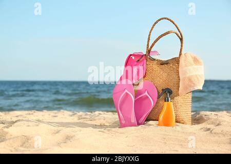 Borsa con flip-flop, costume da bagno, asciugamano, occhiali da sole e cosmetici e sulla spiaggia di sabbia Foto Stock