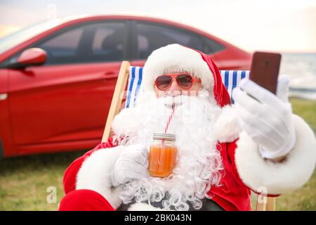 Cool Babbo Natale con cocktail tenendo selfie su Riverside Foto Stock