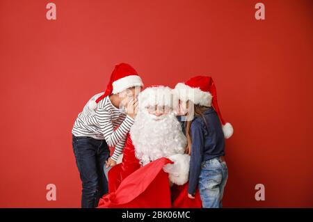 I bambini raccontando Santa i loro desideri contro il colore di sfondo Foto Stock