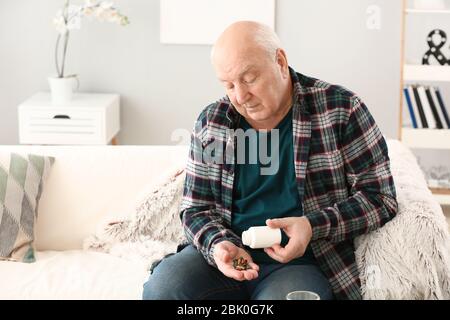 Uomo anziano con le pillole a casa Foto Stock