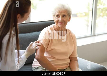 Medico dando donna diabetica iniezione di insulina a casa Foto Stock