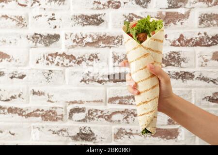 Mano femmina con gustosi falafel pita contro un muro di mattoni Foto Stock