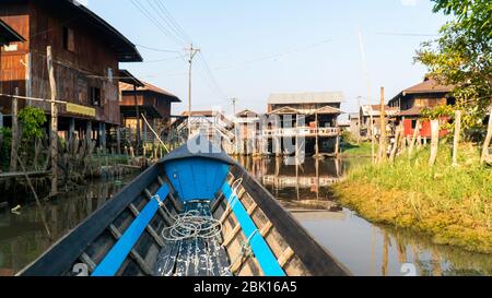 Nyaungshwe, Myanmar : 12 marzo 2020 - giro in barca a coda lunga sul canale del lago Inle in un piccolo villaggio rurale con case su palafitte in acqua Foto Stock